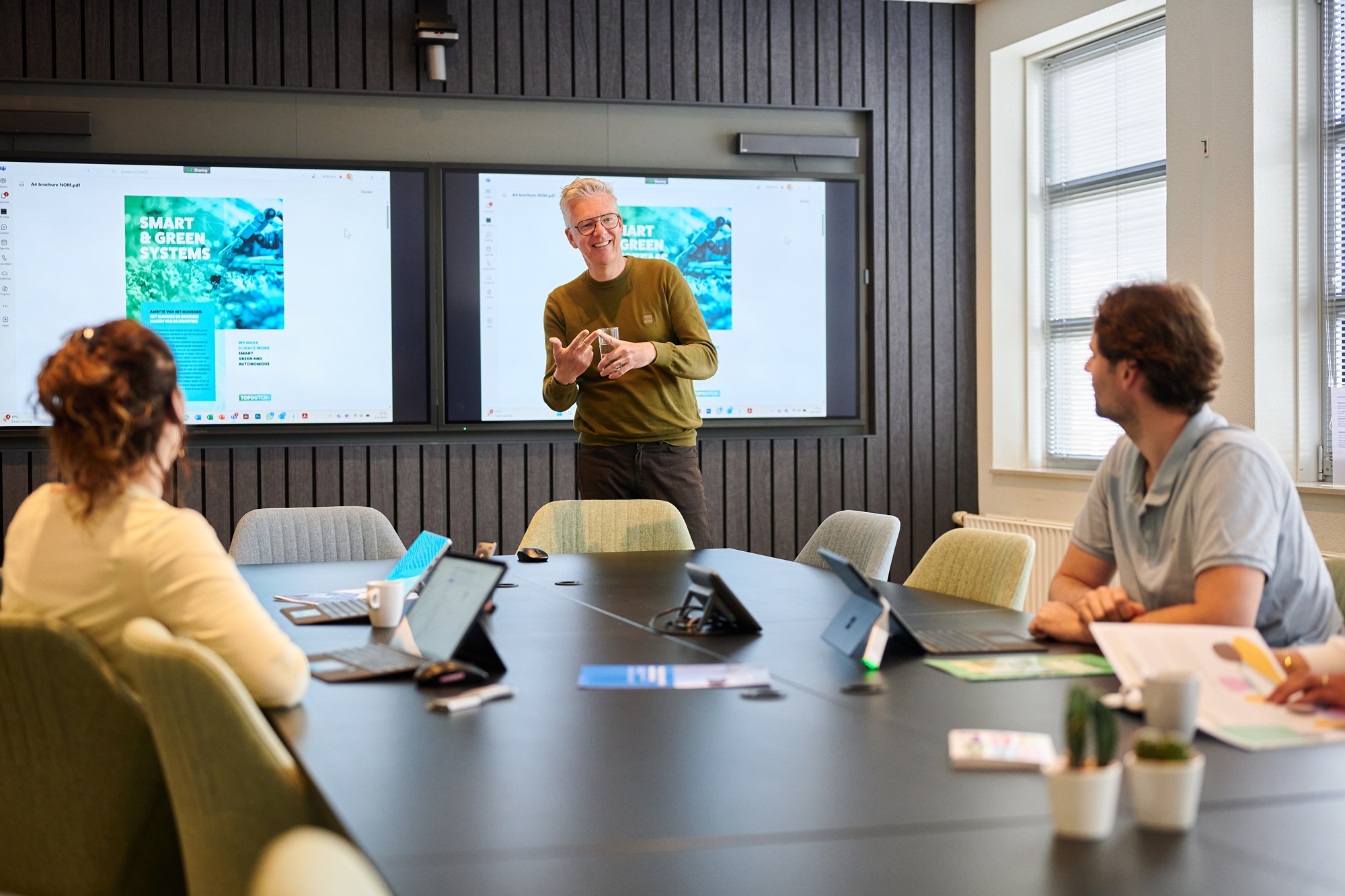 NOM collega's met elkaar in gesprek op het kantoor van de NOM
